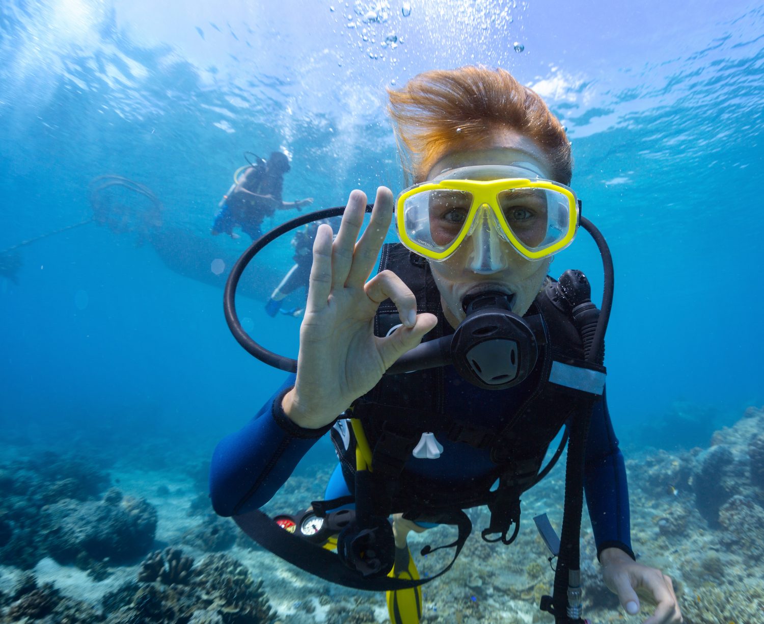 Female scuba diver underwater showing ok signal